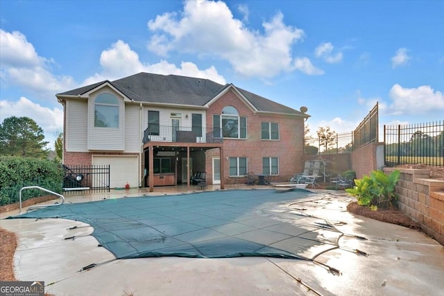 back of house with a patio, a balcony, a garage, and a covered pool