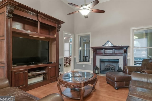 living room with a high end fireplace, light hardwood / wood-style floors, and plenty of natural light