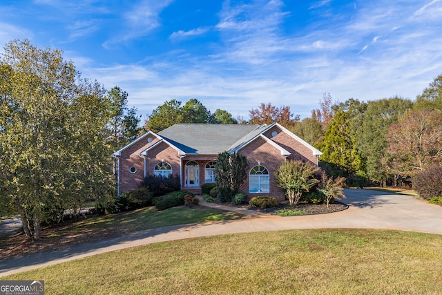 view of front of home featuring driveway, brick siding, and a front yard