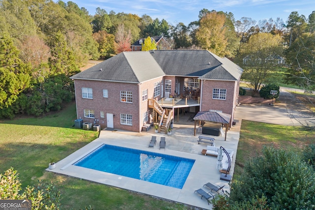 rear view of property with an outdoor pool, a lawn, a patio, stairs, and brick siding