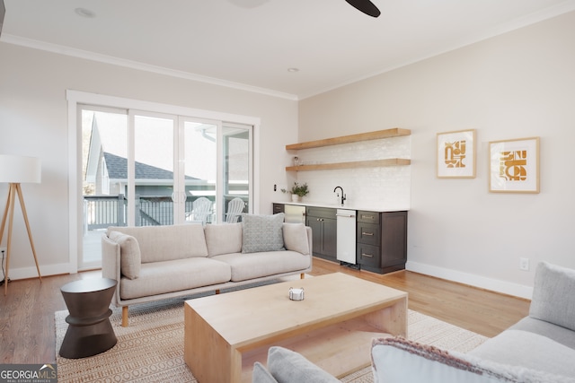 living room with sink, light hardwood / wood-style floors, and ornamental molding