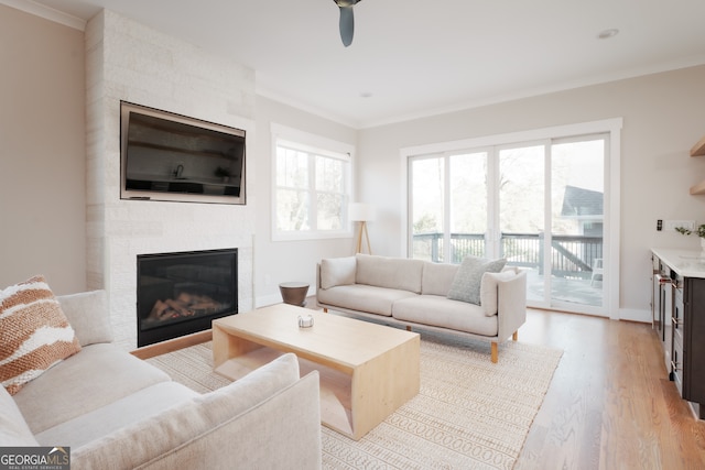 living room with a fireplace, plenty of natural light, ornamental molding, and light hardwood / wood-style flooring