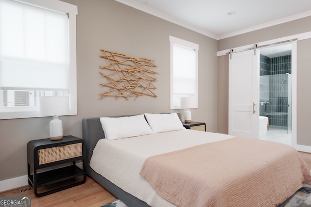 bedroom with a barn door, ensuite bathroom, hardwood / wood-style flooring, and crown molding