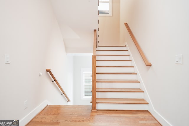 stairway featuring plenty of natural light and hardwood / wood-style floors