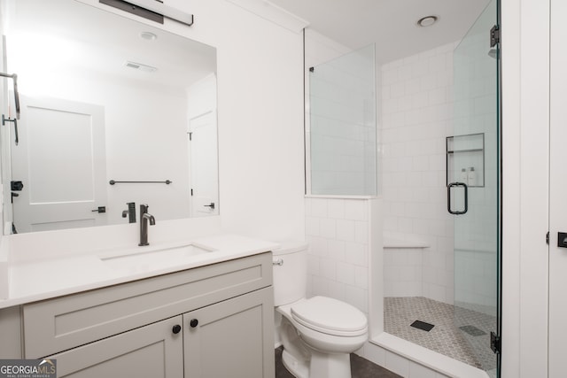 bathroom featuring vanity, a shower with shower door, and toilet