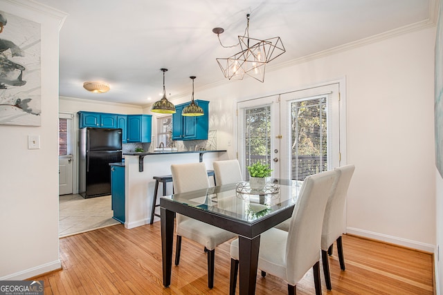 dining room with crown molding, light hardwood / wood-style flooring, french doors, and a notable chandelier