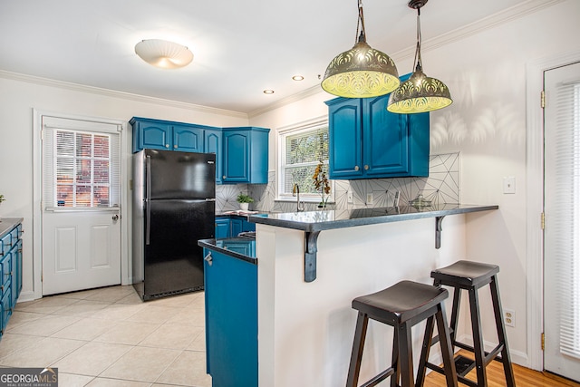 kitchen with a kitchen breakfast bar, black fridge, blue cabinetry, decorative light fixtures, and kitchen peninsula