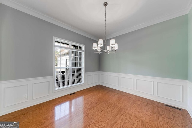 unfurnished dining area featuring crown molding, light hardwood / wood-style flooring, and a notable chandelier