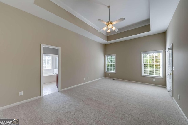 carpeted spare room featuring ceiling fan, crown molding, and a tray ceiling