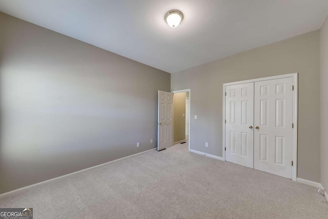 unfurnished bedroom featuring light colored carpet and a closet