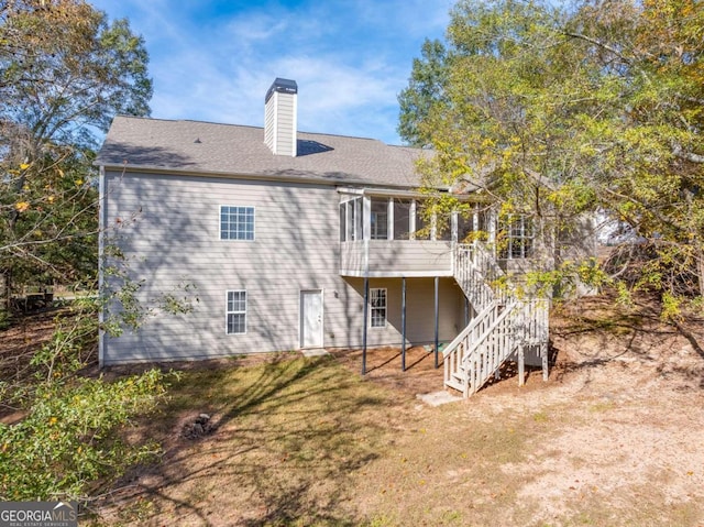 rear view of property with a deck, a sunroom, and a lawn