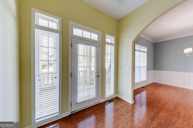 doorway to outside featuring a healthy amount of sunlight, crown molding, and light hardwood / wood-style flooring