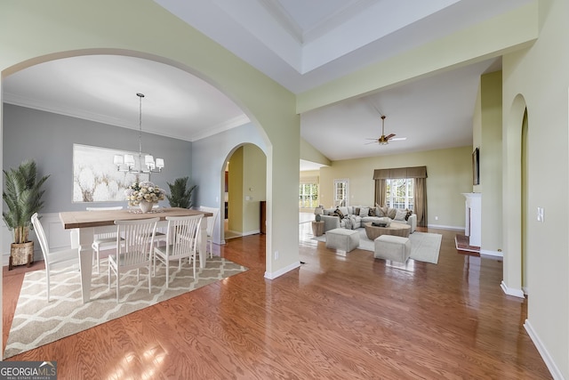 dining area featuring crown molding, lofted ceiling, wood-type flooring, and ceiling fan with notable chandelier