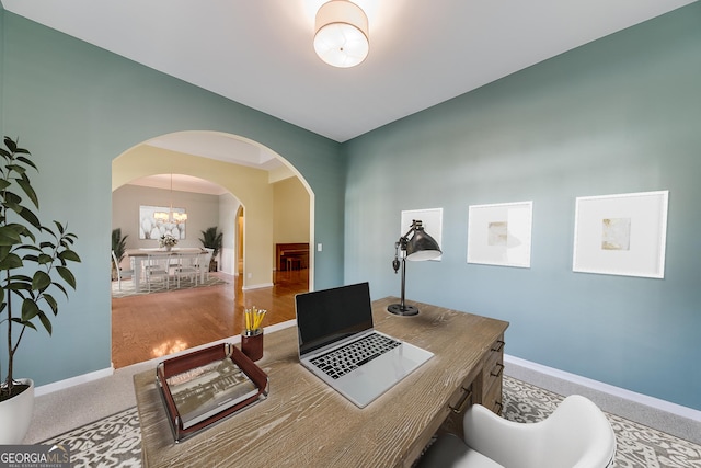 office space with an inviting chandelier and carpet