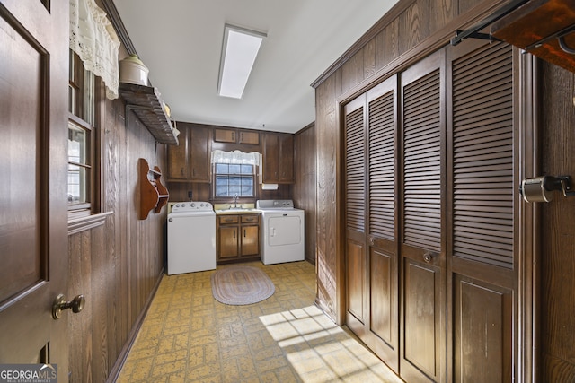 kitchen with dark brown cabinetry, washer and clothes dryer, wooden walls, and sink