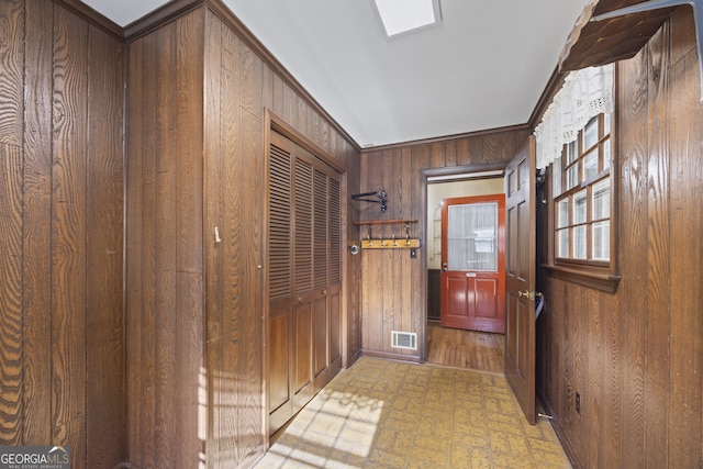 doorway featuring wooden walls and crown molding