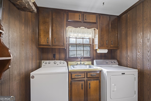 laundry area featuring washing machine and clothes dryer, wood walls, sink, and cabinets