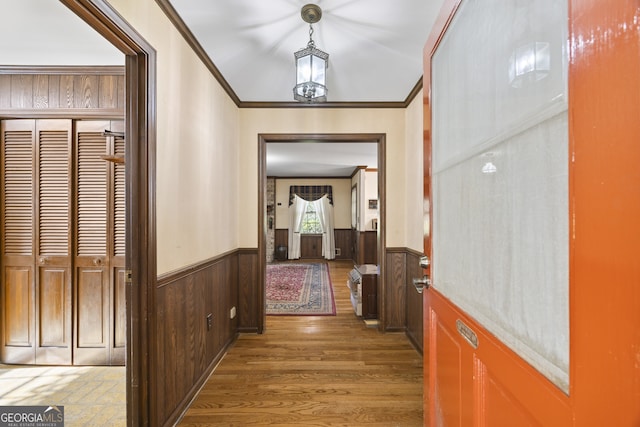 corridor featuring dark hardwood / wood-style floors, ornamental molding, and wooden walls