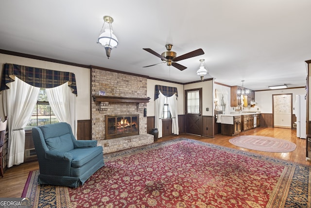 living room featuring a brick fireplace, ornamental molding, ceiling fan, wooden walls, and hardwood / wood-style flooring