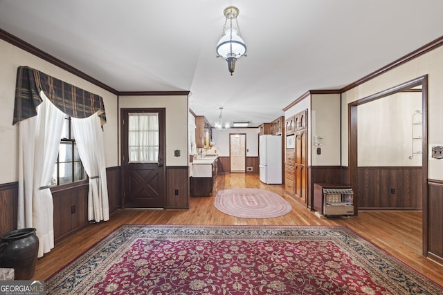 foyer entrance with hardwood / wood-style floors, an inviting chandelier, and ornamental molding