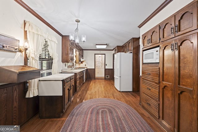 kitchen with ornamental molding, white appliances, hanging light fixtures, and light hardwood / wood-style flooring