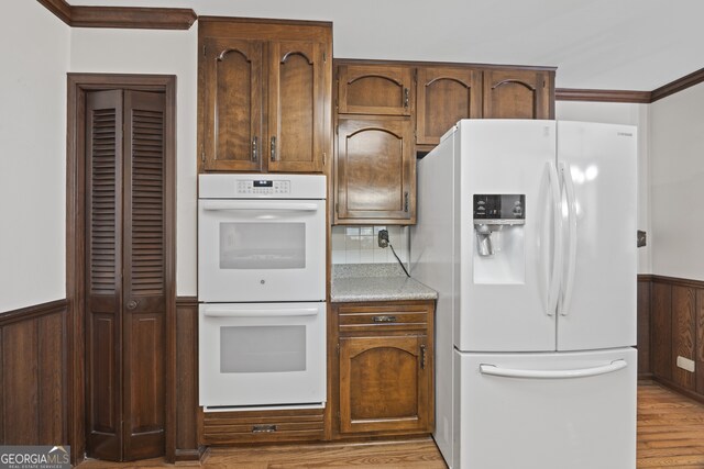 kitchen featuring wood walls, crown molding, light hardwood / wood-style floors, and white appliances