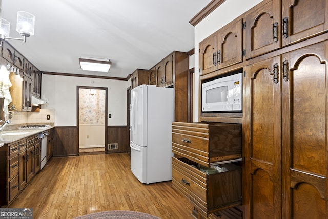 kitchen featuring sink, light hardwood / wood-style floors, white appliances, decorative backsplash, and exhaust hood