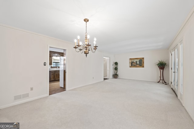 carpeted empty room with an inviting chandelier and ornamental molding