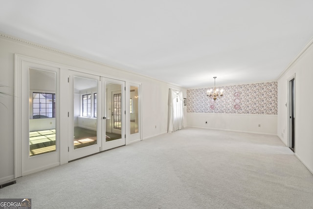 carpeted spare room featuring ornamental molding and an inviting chandelier