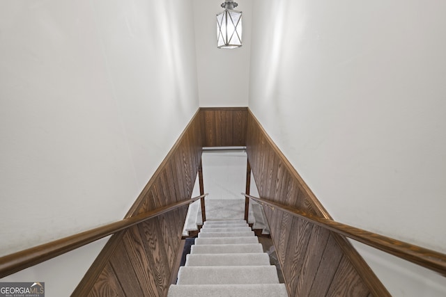 stairway featuring wooden walls