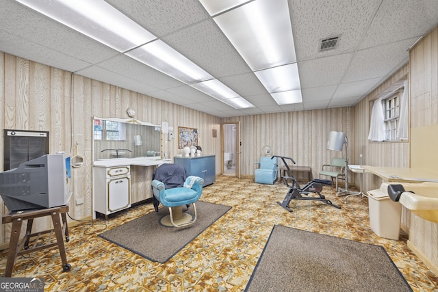 workout room with a paneled ceiling and wooden walls