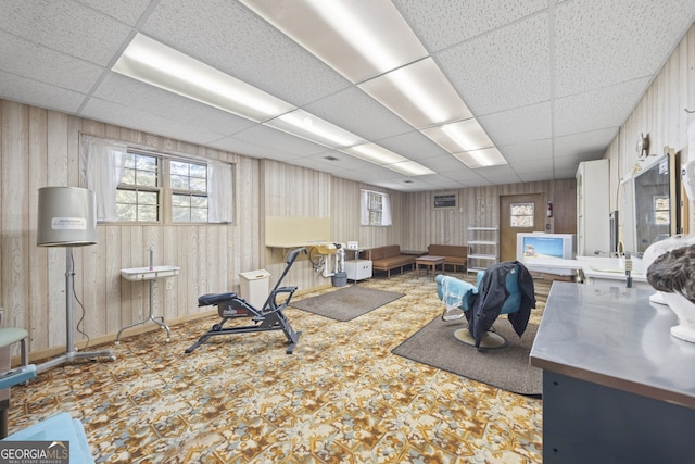 interior space with a paneled ceiling, wood walls, and sink