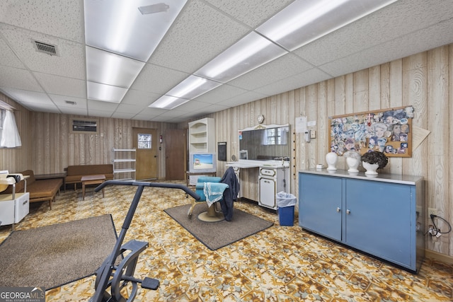 game room with a drop ceiling and wood walls