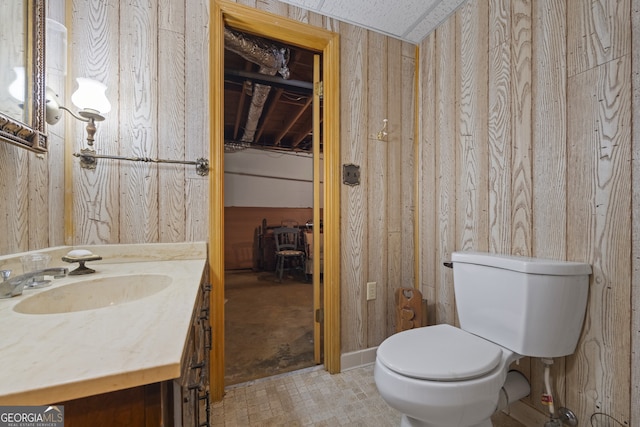 bathroom with vanity, wood walls, and toilet