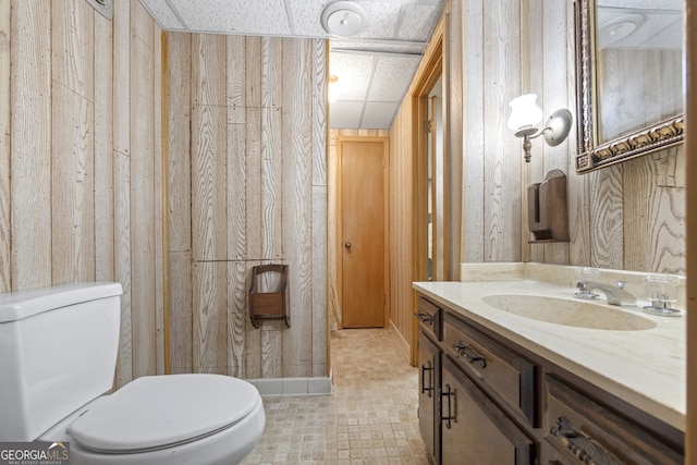 bathroom featuring wood walls, tile patterned flooring, vanity, and toilet