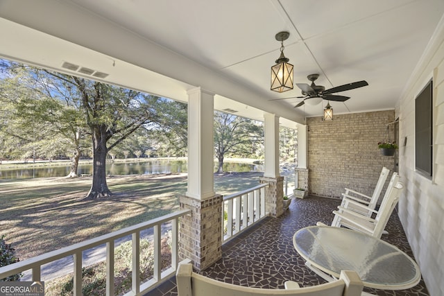 balcony with covered porch, a water view, and ceiling fan