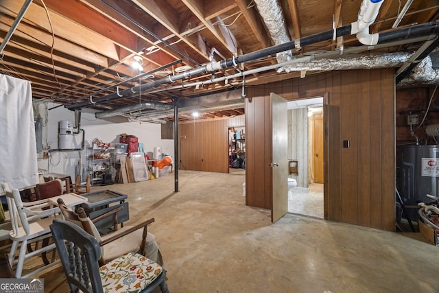 basement featuring wood walls and water heater