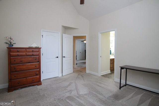 carpeted bedroom with high vaulted ceiling and connected bathroom