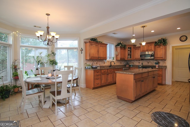 kitchen with decorative backsplash, a center island, sink, and a notable chandelier