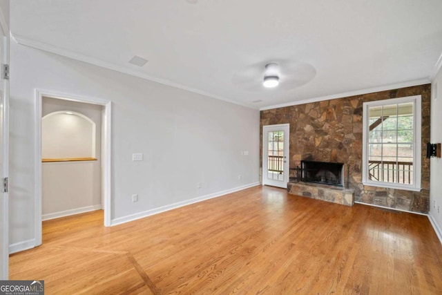 unfurnished living room featuring ceiling fan, light hardwood / wood-style floors, a stone fireplace, and crown molding