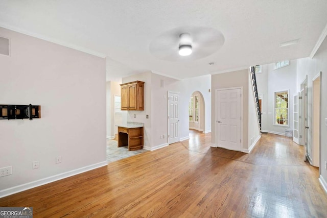 interior space with ceiling fan, light wood-type flooring, and ornamental molding