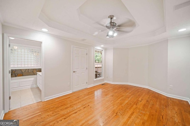 unfurnished room with light hardwood / wood-style floors, ceiling fan, and a tray ceiling