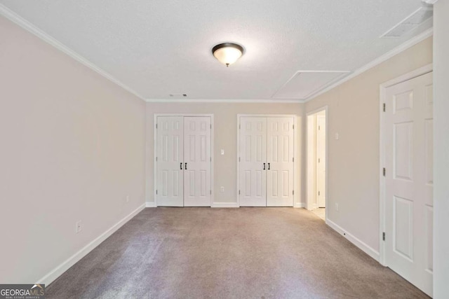 unfurnished bedroom featuring ornamental molding, carpet floors, a textured ceiling, and two closets