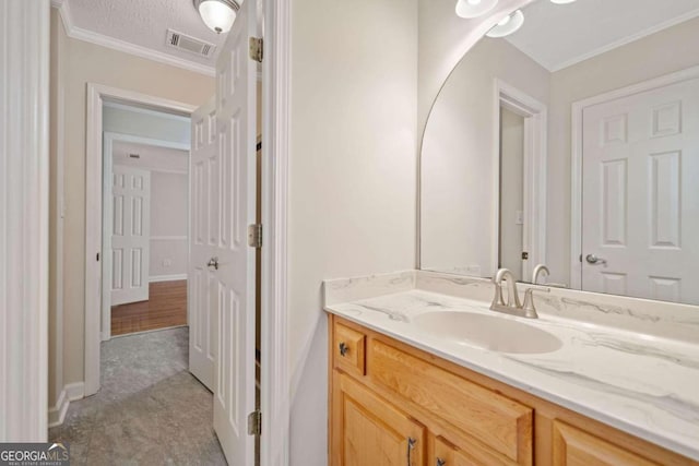 bathroom with hardwood / wood-style floors, vanity, a textured ceiling, and ornamental molding