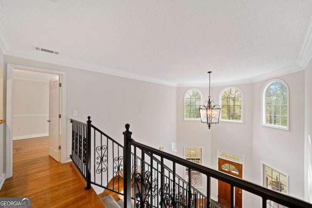 hallway featuring wood-type flooring, an inviting chandelier, and ornamental molding