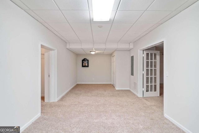 spare room featuring a paneled ceiling and light colored carpet