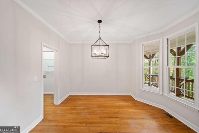 empty room with light hardwood / wood-style flooring, an inviting chandelier, and crown molding