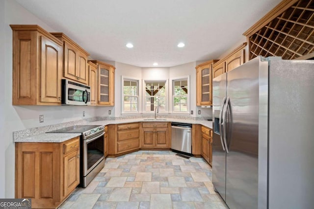 kitchen with light stone counters, sink, and appliances with stainless steel finishes