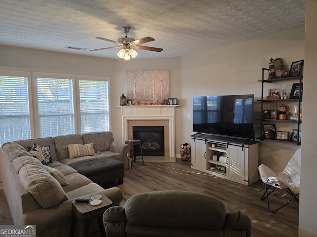 living room with ceiling fan, dark wood-type flooring, and a textured ceiling