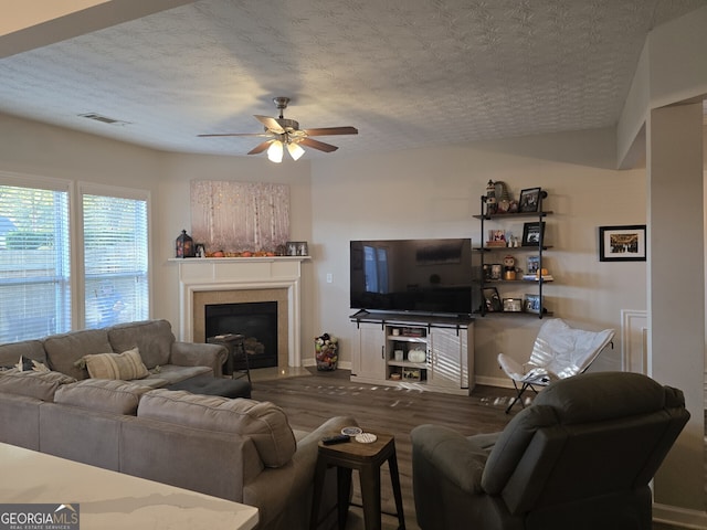 living room featuring dark hardwood / wood-style floors, ceiling fan, and a textured ceiling